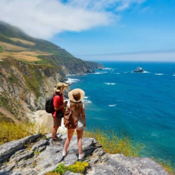 Friends relaxing on hiking trip by the Pacific ocean. People enjoying beautiful coastal scenery. People looking at beautiful ocean view. Pacific Ocean, Big Sur, California, USA